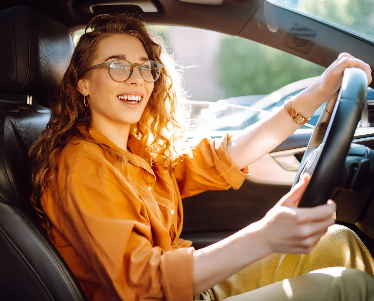 woman driving a car, smiling in the sun